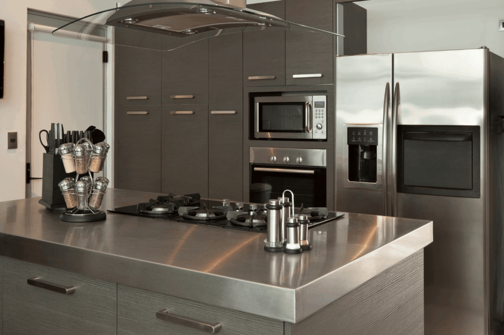 Sleek modern kitchen with dark wood cabinetry, stainless steel appliances, and a central island cooktop beneath a curved glass range hood; a minimalist, ergonomic space blending contemporary design with culinary functionality.