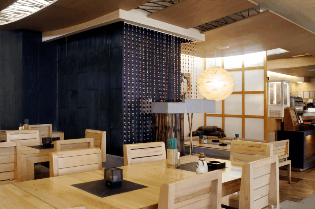 Japanese minimalist interior restaurant design blending refined restaurant interior design and functional restaurant design with subtle Singapore restaurant design influences, showcasing clean interior design that supports smooth operations in a serene restaurant space. Light wood dining tables and chairs create harmony, evoking the intimacy of a house while curated art pieces create cultural links from London to Singapore. A warm atmosphere welcomes customers with thoughtful ideas for a discreet bar, prime location, and versatile venue offering inspiration for hospitality professionals seeking perfect ambiance and minimalist decor. Designed for guests to enjoy life, the ambience enhances service to cater to family gatherings in an appealing sense of style, offering tips to plan adaptable offices or strengthen a brand design. The layout invites visitors to relax and reflect on projects seen in galleries, ensuring accessibility for every journey with dim lighting, high functionality, and precise details in architecture that connect to nature. Smart operations integrate discreet ventilation and plants for balance; for instance, the balance of flow and optimal form mirrors the world's best venues to visit and spark appetite. Thoughtful ramps show understanding of mistakes to avoid for disabilities, preventing delays in kitchen workflow. This important ideal of comfort supports staff in an open place that embodies timeless Japanese minimalism while accommodating cooking, hotel-level service, and design excellence.