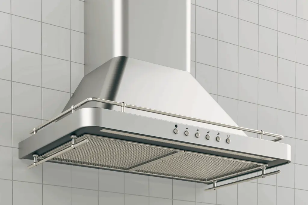 Close-up of a modern stainless steel kitchen range hood mounted on a tiled wall in a Singapore commercial kitchen. Features include mesh grease filters, control panel with fan and light settings, and a sleek chimney design—illustrating key ventilation components essential for managing heat and humidity in tropical climates.