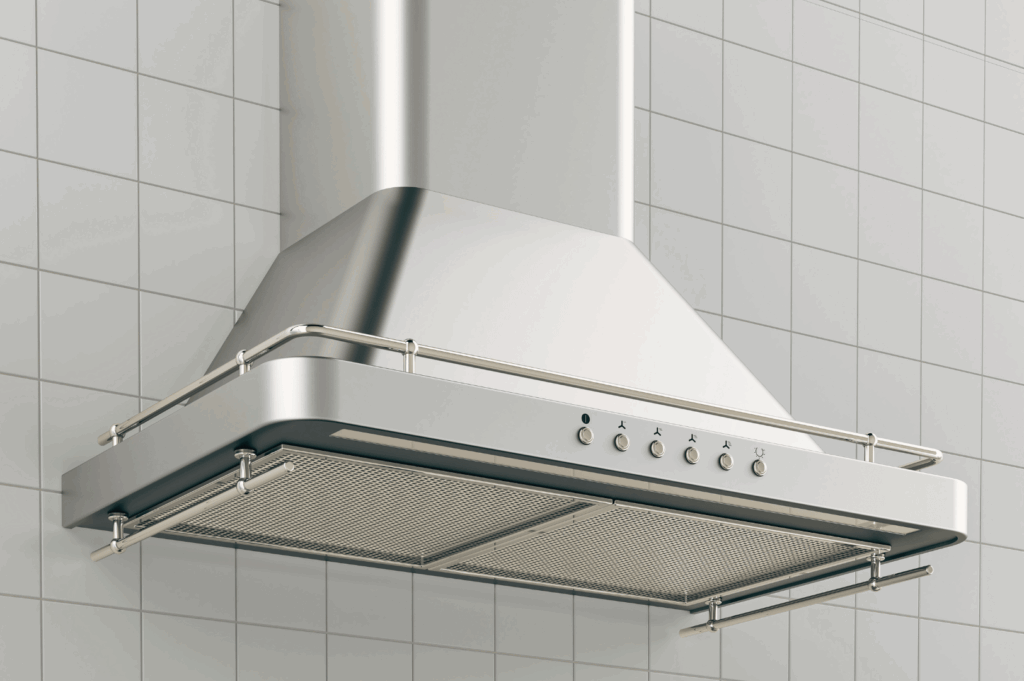 Close-up of a modern stainless steel kitchen range hood mounted on a tiled wall in a Singapore commercial kitchen. Features include mesh grease filters, control panel with fan and light settings, and a sleek chimney design—illustrating key ventilation components essential for managing heat and humidity in tropical climates.