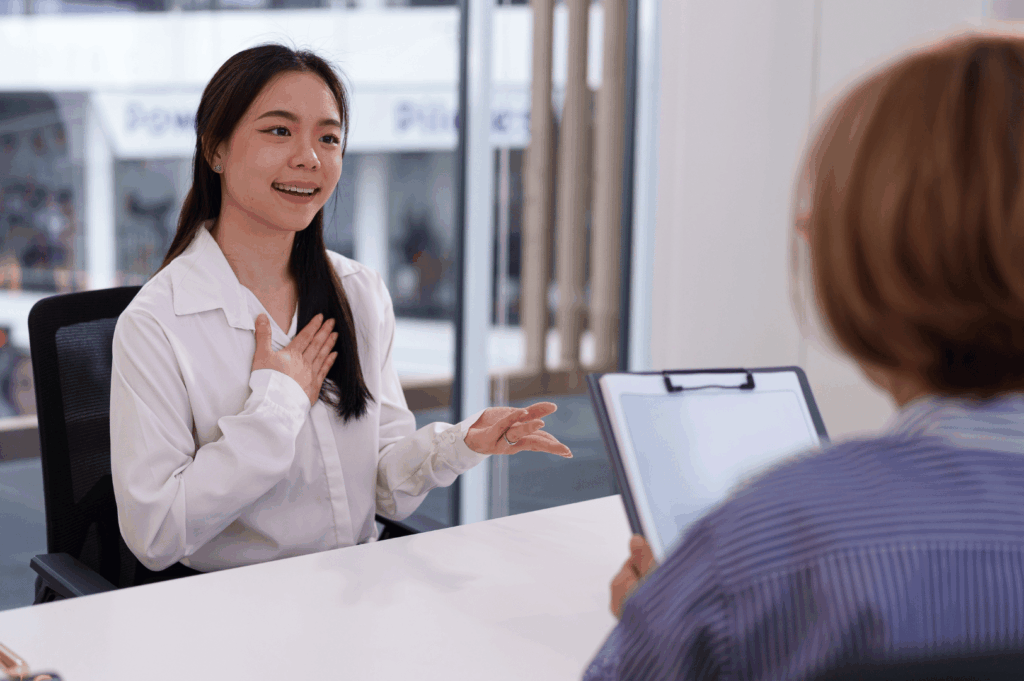 Two people meet at a desk for an interview for contractor selection, with interviewer having her notes open.