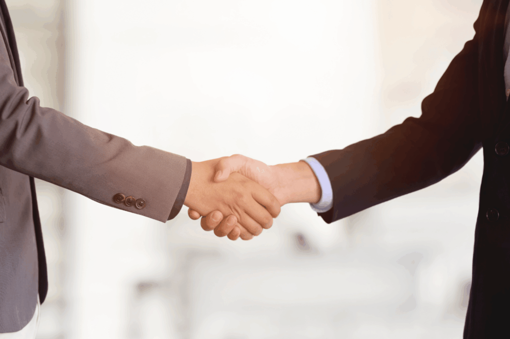Two professionals shaking hands in a modern office, symbolizing a successful contractor selection for a restaurant renovation project
