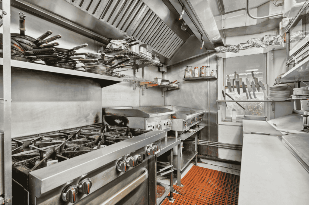 Commercial kitchen with stainless steel stoves, grills, and open shelving, showing an efficient layout for staff comfort and smooth workflow in a Singapore setting.