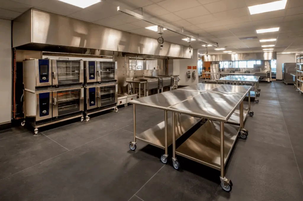 Spacious commercial kitchen in Singapore with stainless steel worktables, ovens, and ventilation, designed for smooth workflow and staff comfort.