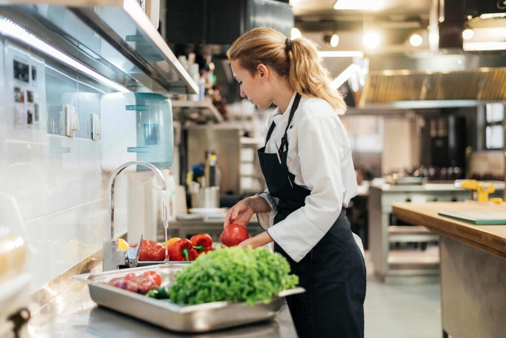 A chef cleaning vegetables on its dedicated sinks to avoid cross contaminating with other ingredients.