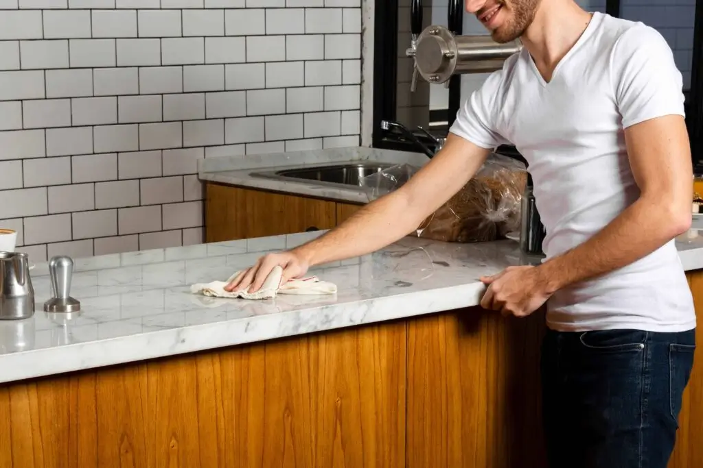 A picture of a staff member wiping the countertop, making it presentable for the next diner.