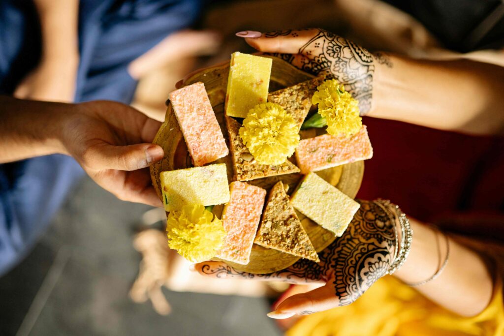 An overhead shot of a woman serving a famous Hindu delicacy to another individual.