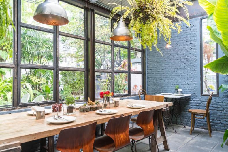 A dining area laced with earthy colors accompanied with a vast number of plants and woodwork.