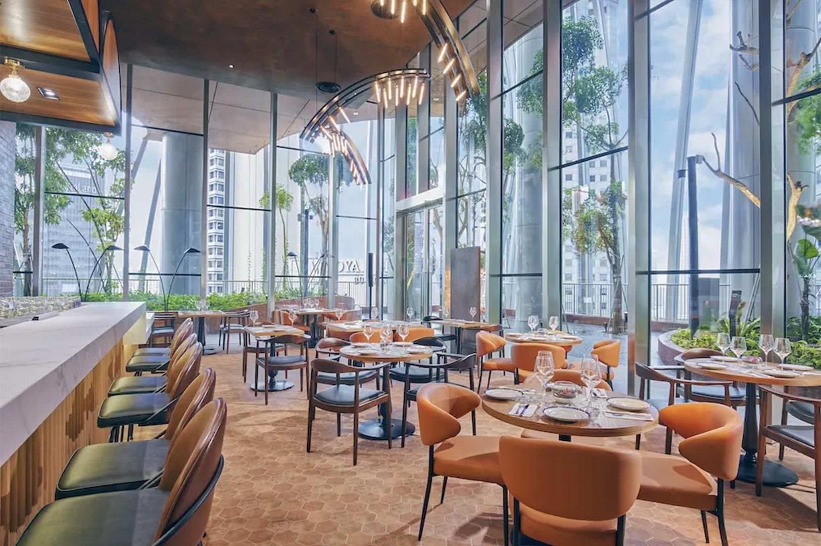 Spacious luxury fine dining area with high ceilings, floor-to-ceiling windows offering city views, hexagonal floor tiles, and contemporary orange leather chairs.