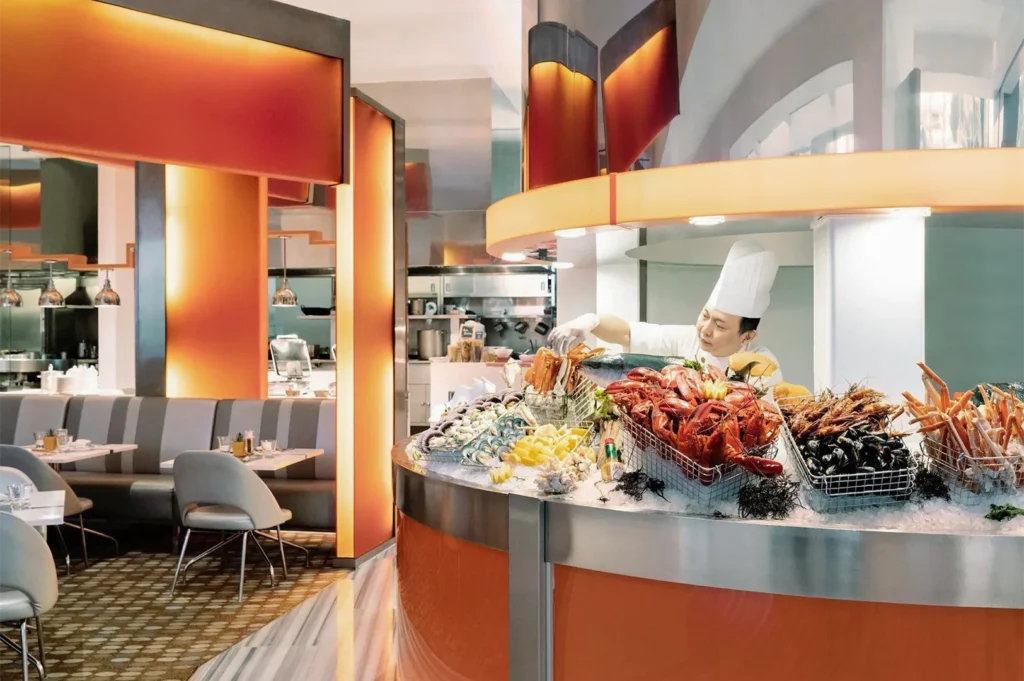 A professional chef preparing a fresh seafood display featuring lobsters, prawns, and crab legs at a buffet.
