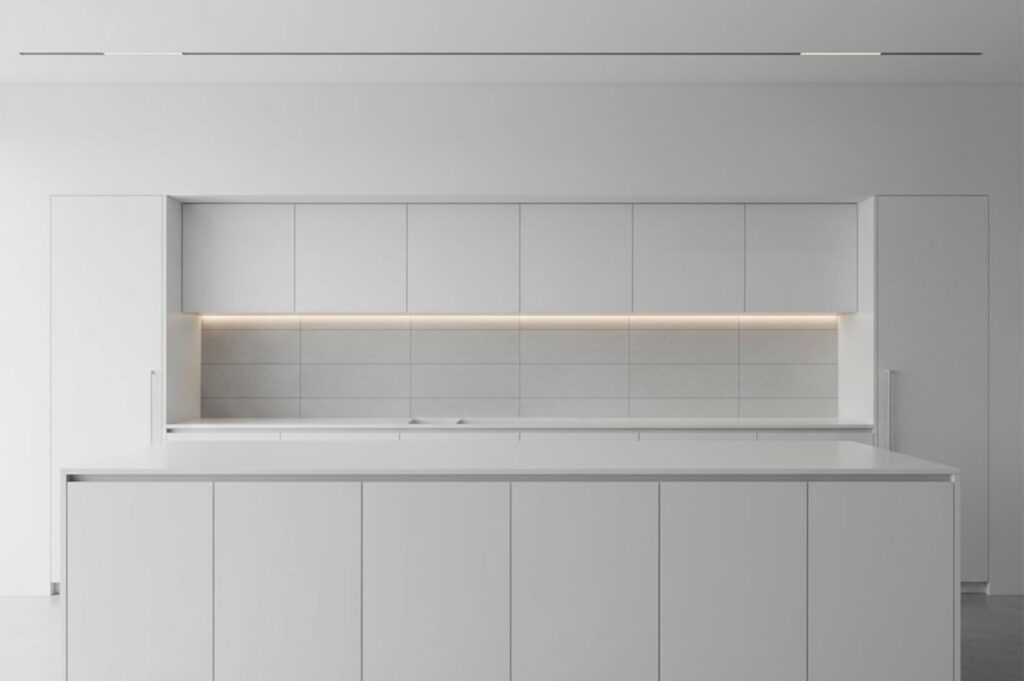 A seamless, ultra-minimalist all-white kitchen featuring handleless cabinetry, a hidden backsplash with warm LED strip lighting, and a monolithic white island.