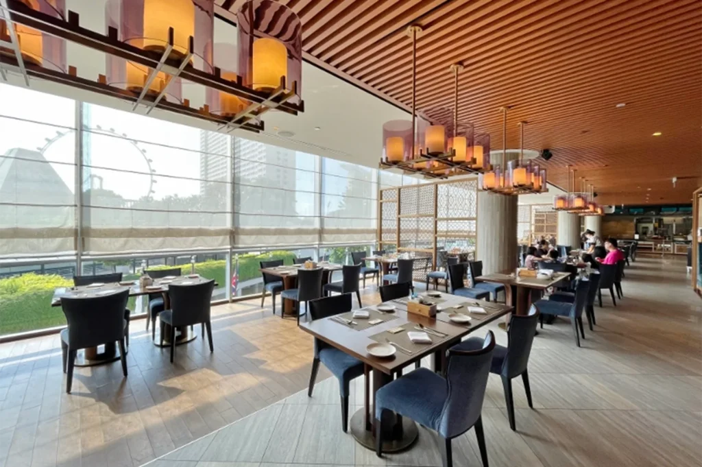 Upscale dining room with floor-to-ceiling windows overlooking a city skyline and the Singapore Flyer.