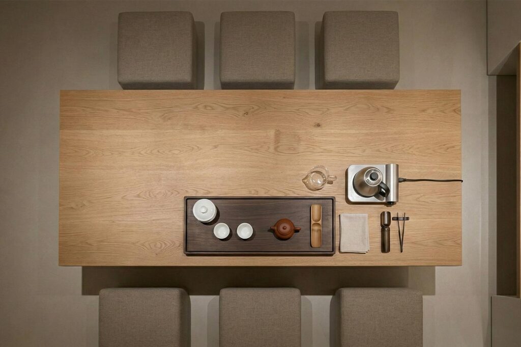 An overhead top-down view of a traditional Gongfu tea set, electric kettle, and wooden tray neatly arranged on a light oak table.