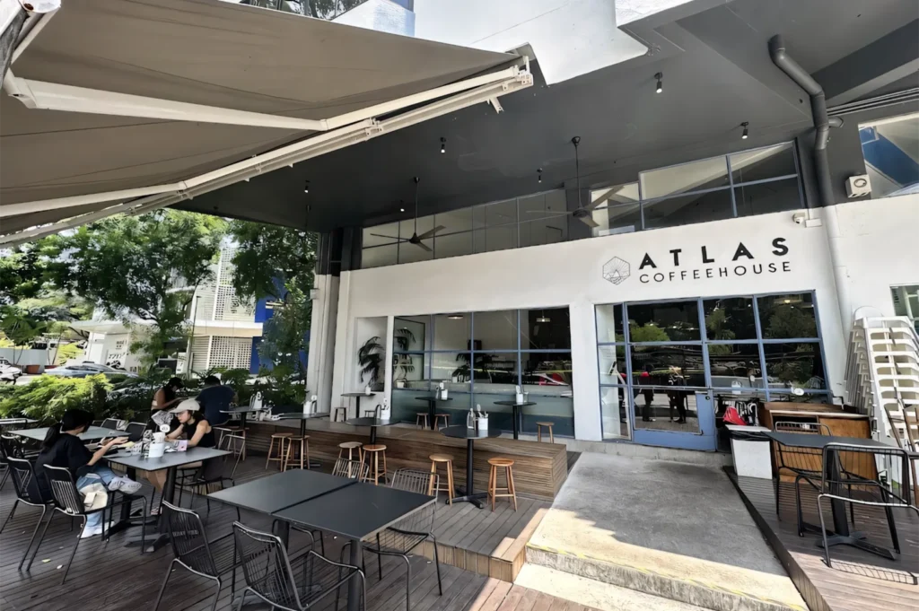 The exterior storefront of Atlas Coffeehouse with outdoor wooden deck seating and large glass windows.