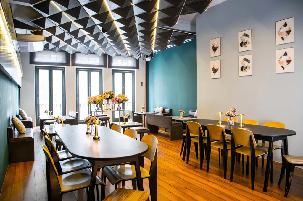 A modern bistro dining room featuring a unique dark geometric 3D ceiling and teal accent walls.