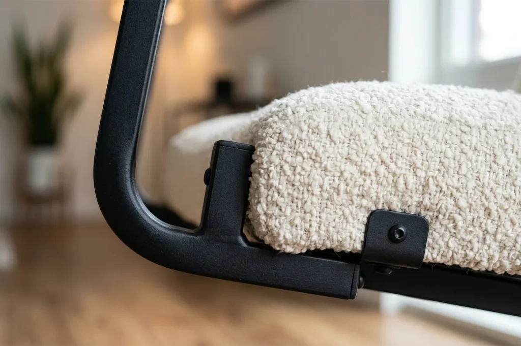 Detailed close-up showing the texture of white boucle upholstery attached to a sleek matte black metal chair frame with visible industrial bolt accents.