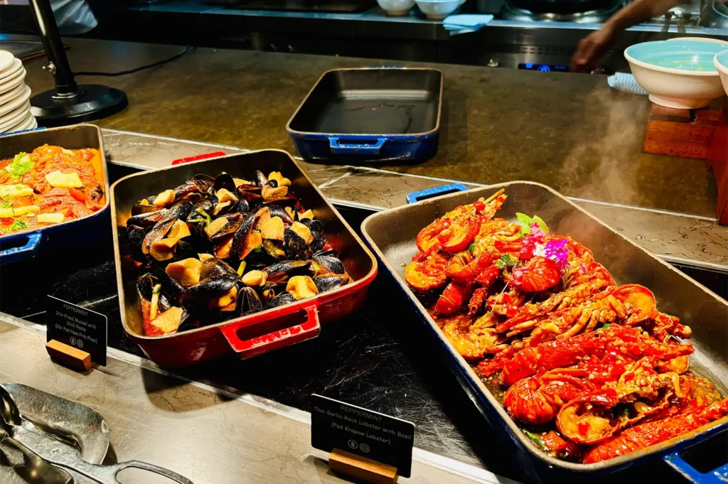 Trays of Thai garlic rock lobster with basil and stir-fried mussels with chili paste displayed at Peppermint's buffet station.
