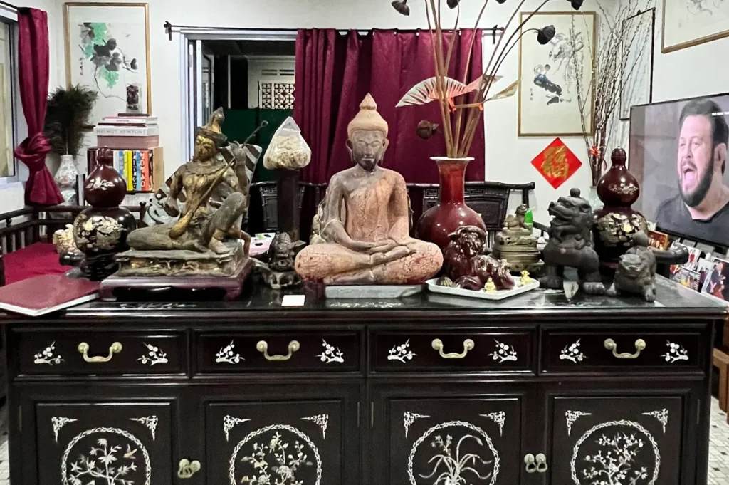 An elegant, dark wooden antique Chinese sideboard cabinet adorned with traditional Buddha statues, oriental vases, and intricate mother-of-pearl inlay designs.