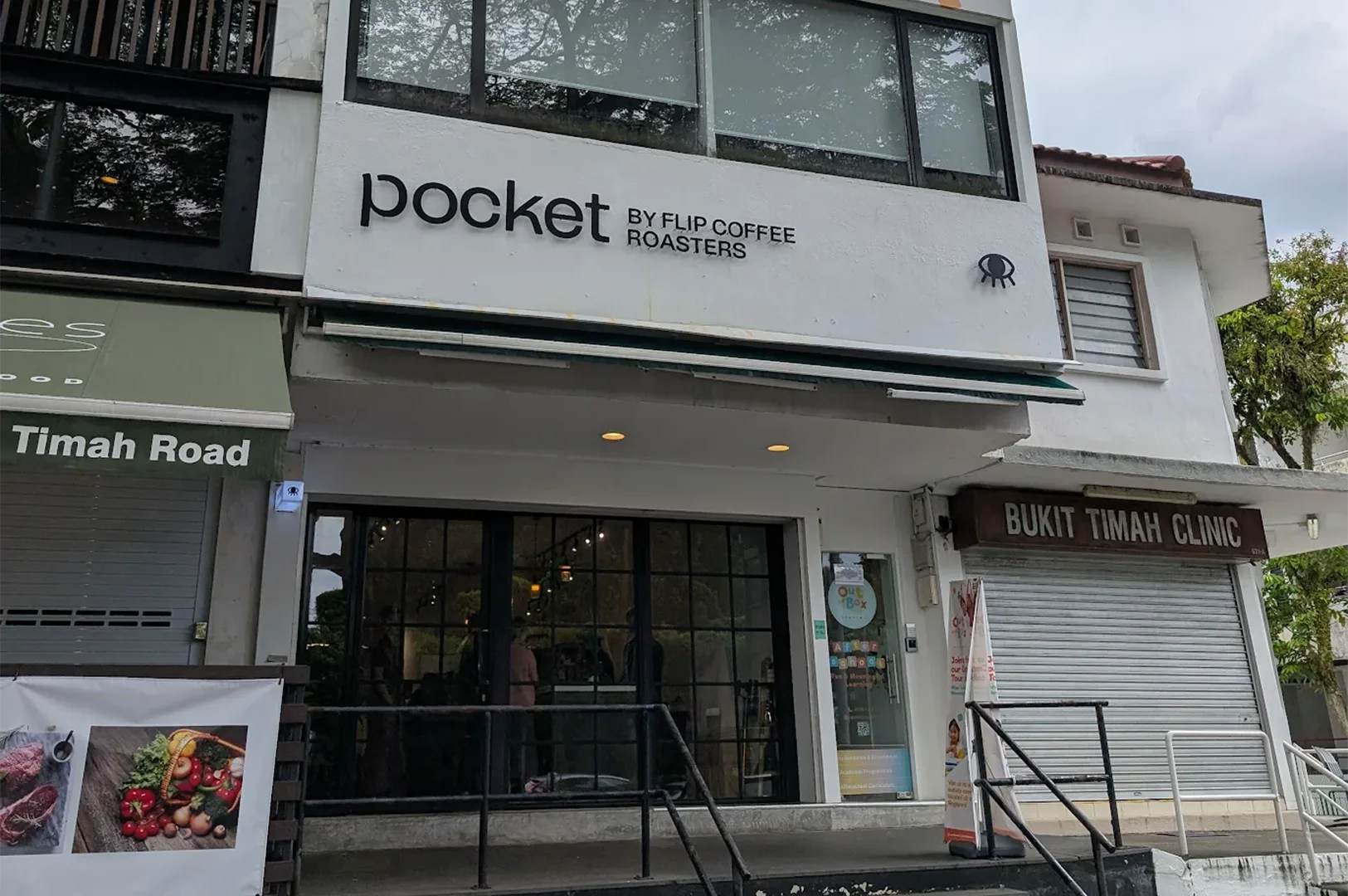 Storefront exterior of Pocket by Flip Coffee Roasters on Bukit Timah Road, showing a modern glass facade next to Bukit Timah Clinic.