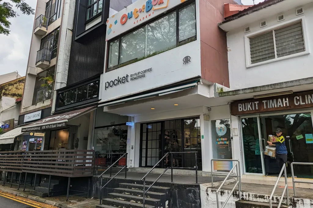 Angled view of Pocket by Flip Coffee Roasters facade with outdoor steps, located underneath Out of Box Academy.