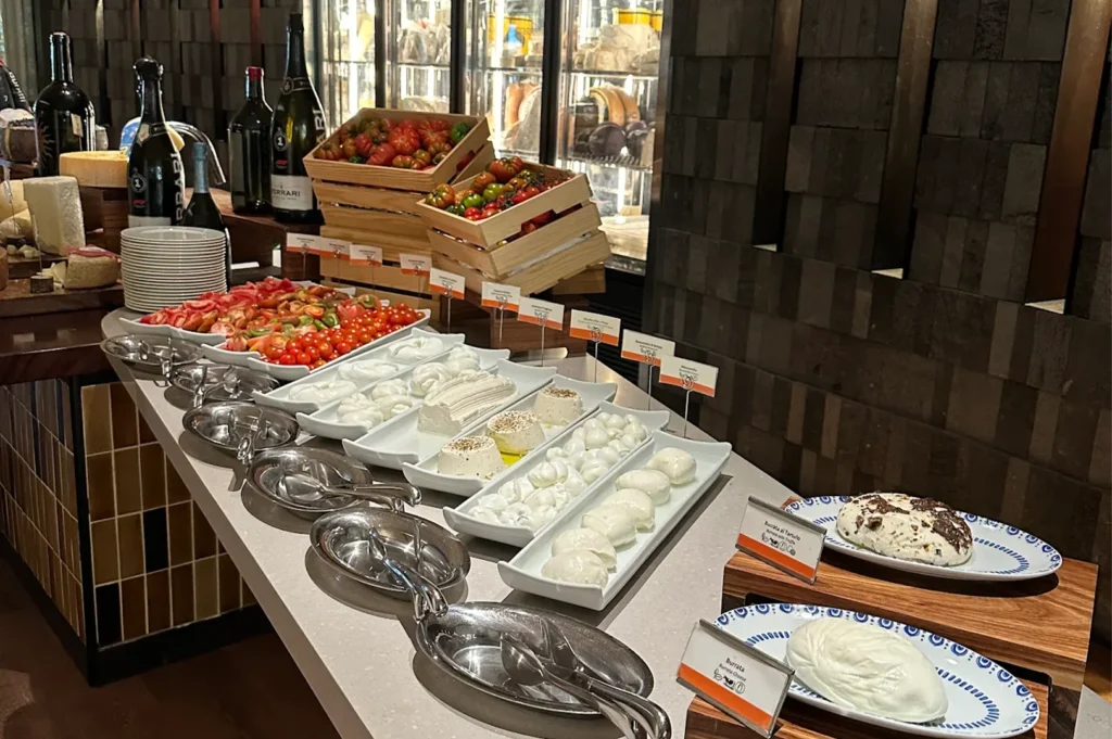 Fresh cheese bar display showcasing multiple varieties of Mozzarella, Stracciatella, and Burrata al Tartufo paired with heirloom tomatoes and Italian olive oils.