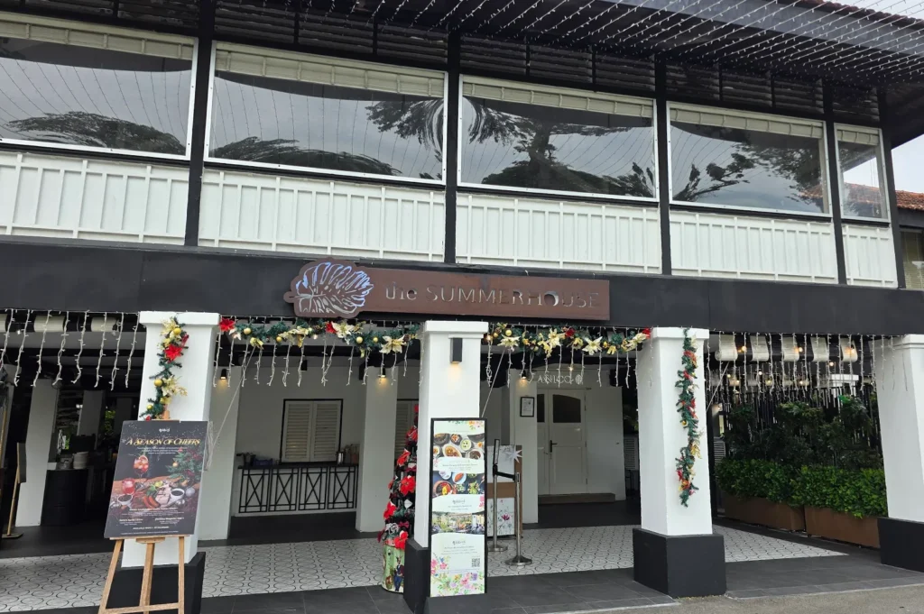 The main entrance facade of The Summerhouse restaurant featuring white pillars decorated with festive Christmas garlands, fairy lights, and a wooden restaurant sign.