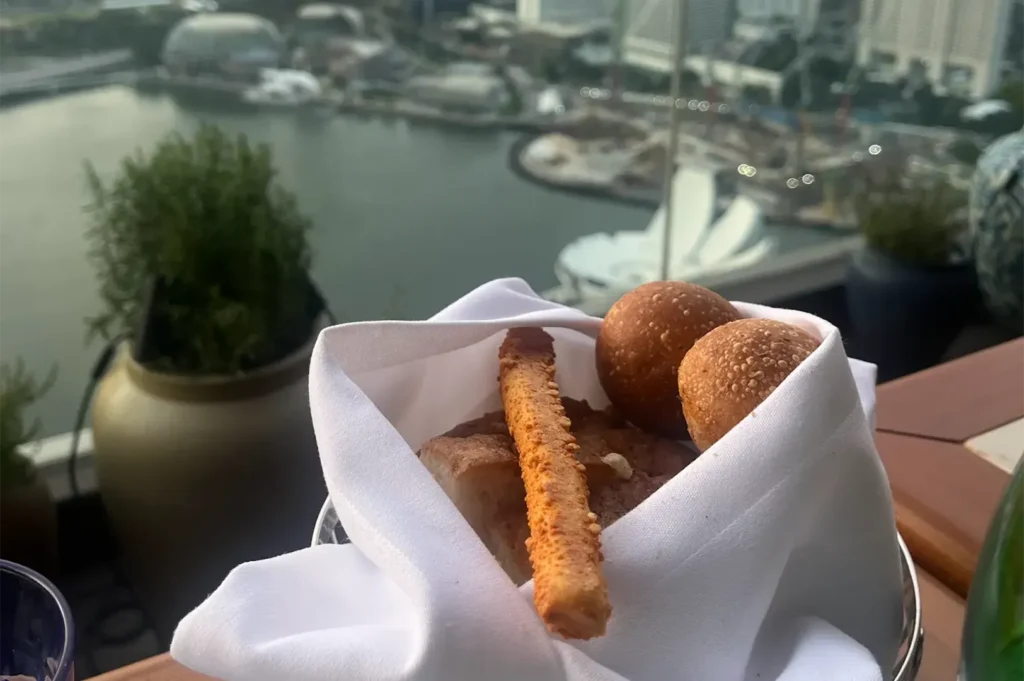 Artisanal complimentary bread basket served at LAVO Singapore rooftop terrace overlooking Marina Bay