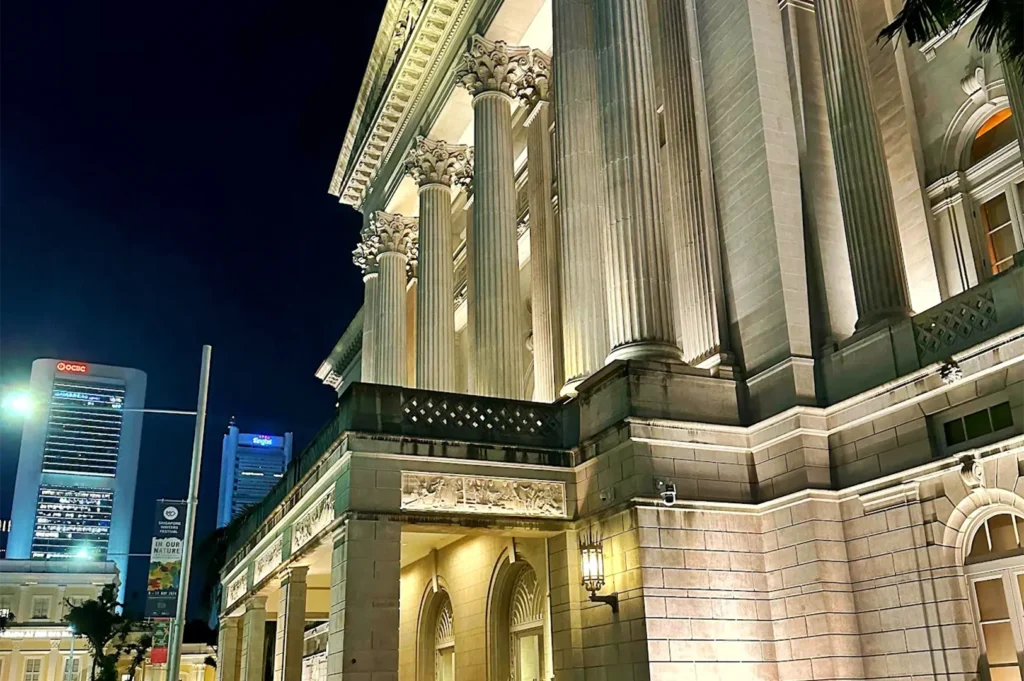 Exterior night view of the historic National Gallery Singapore building featuring illuminated neoclassical columns where Odette is located.