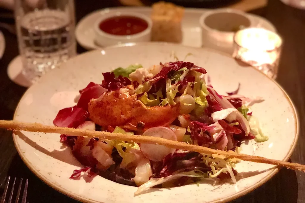 Gourmet lobster salad dish with fresh greens and grissini breadstick at LAVO Singapore