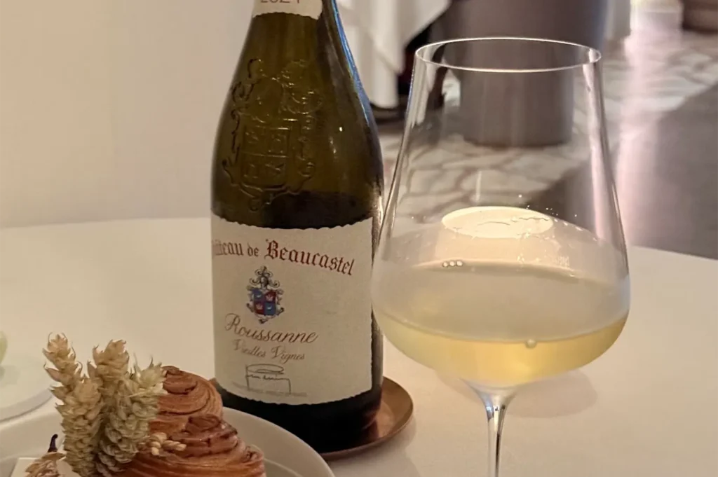 A bottle of Chateau de Beaucastel Roussanne Vieilles Vignes white wine paired with a filled glass and gourmet bread pastry at Odette.