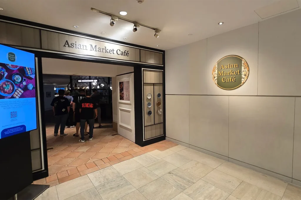 Entrance of Asian Market Cafe with brand signage and decorative wall plates at Fairmont Singapore.