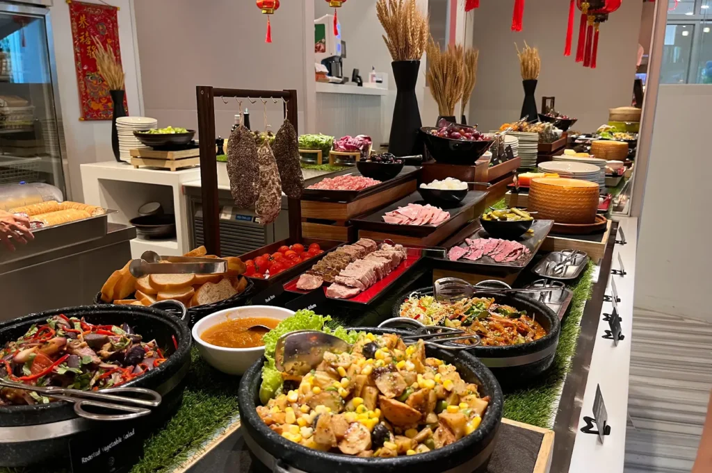 Gourmet buffet selection featuring cured meats, sausages on a rack, cold cuts, and roasted vegetable salad at Shangri-La Singapore.